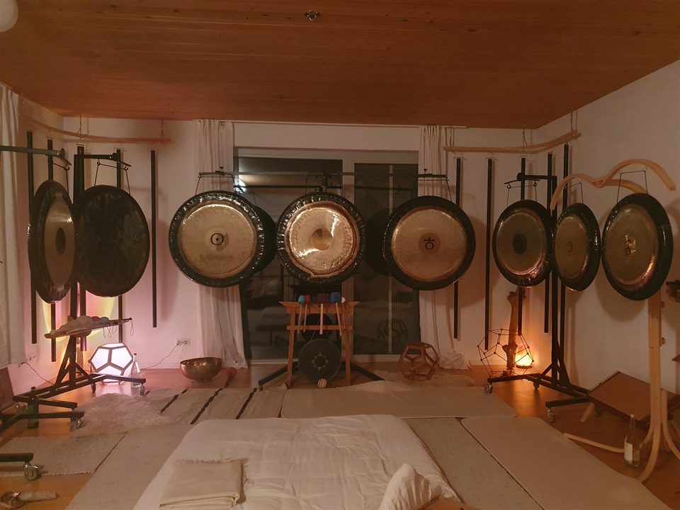 Der Klangraum mit Gongs, Holzdecke und Matten, warmes Abendlicht.