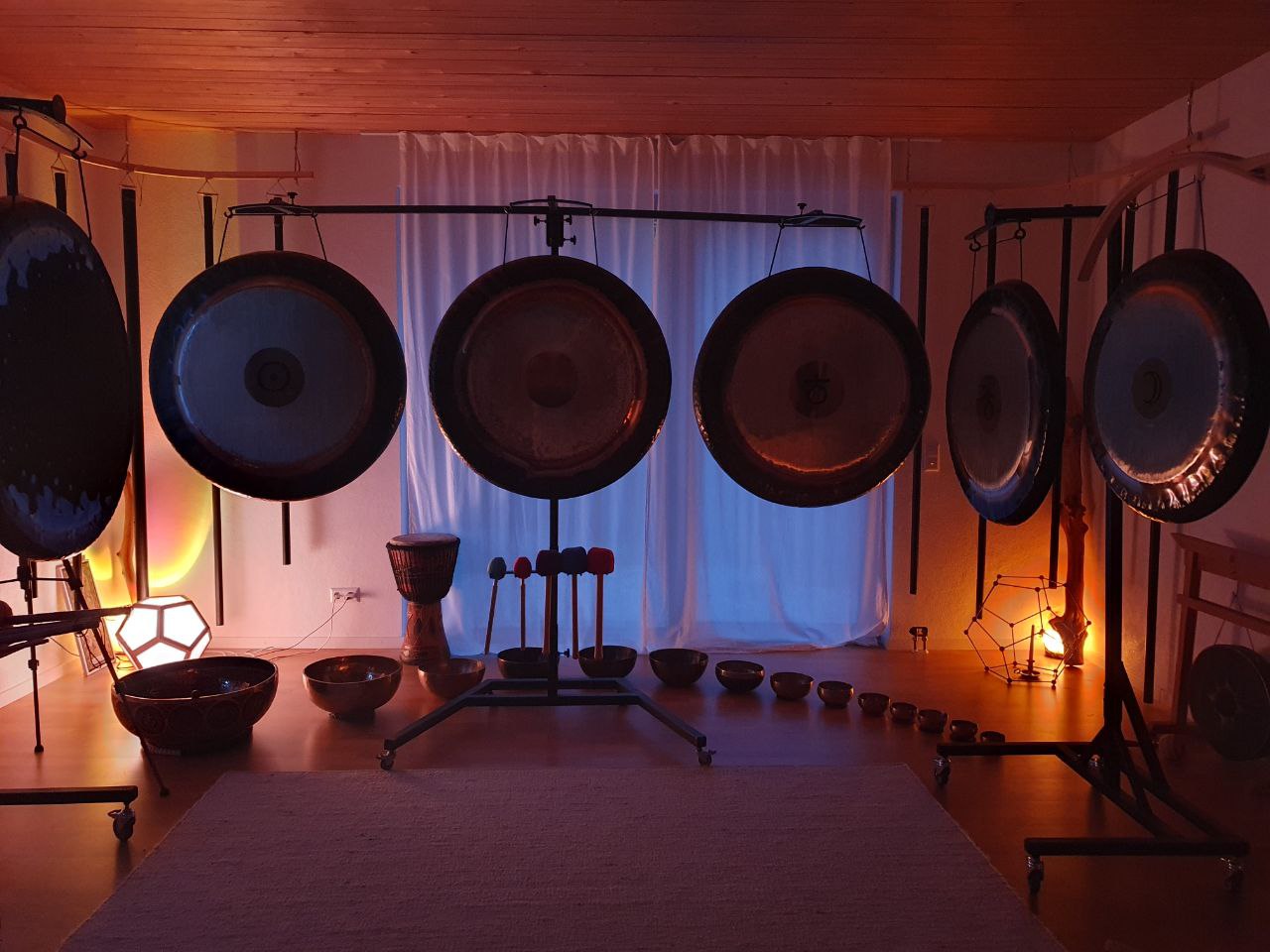 Klangraum mit mehreren Gongs, Klangschalen und Instrumenten, warm beleuchtet.